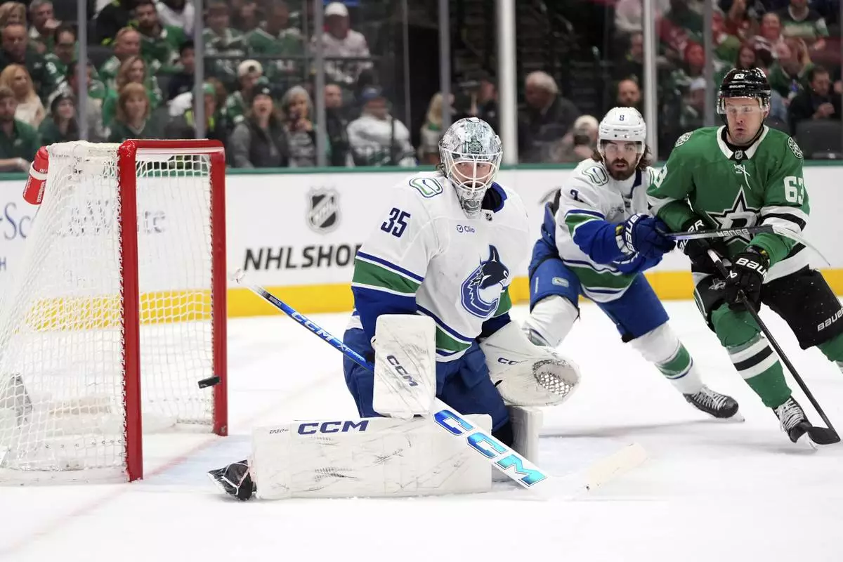FILE - Vancouver Canucks goaltender Thatcher Demko (35) watches a shot go wide of the net as Conor Garland (8) helps against pressure from Dallas Stars right wing Evgenii Dadonov (63) in the first period of an NHL hockey game in Dallas, April 8, 2025. (AP Photo/LM Otero, File)