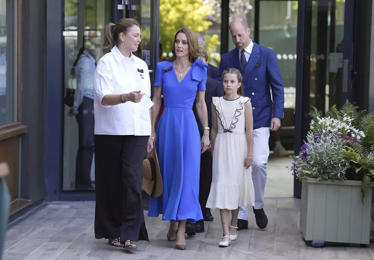 Britain's Prince William, Kate, Princess of Wales, center, and Princess Charlotte are greeted by Sally Ambrose, left, a member of the Committee of Management of The Championships, as they arrive to attend the men's singles final match between Italy's Jannik Sinner and Spain's Carlos Alcaraz at the Wimbledon Tennis Championships in London Sunday July 13, 2025. (Andrew Matthews/Pool via AP)