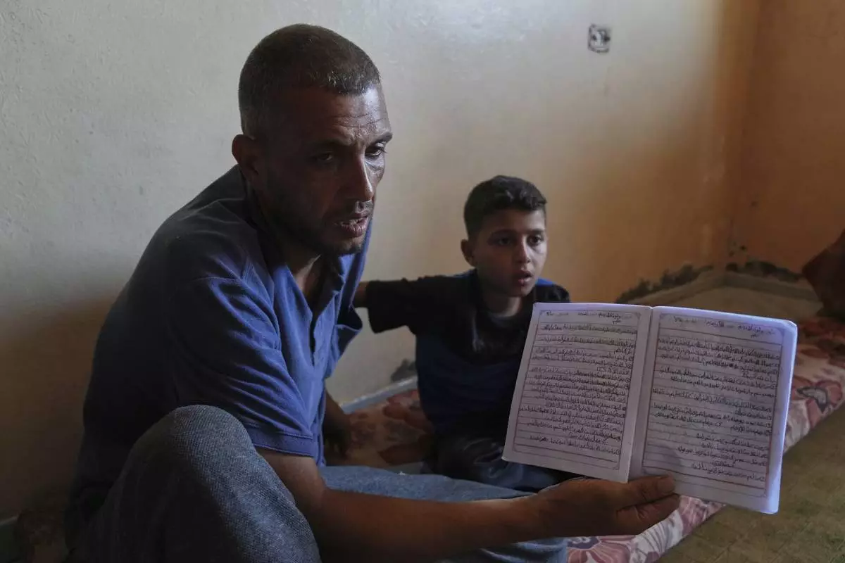 Nidal Al-Nouri shows a school notebook that belonged to his 13-year-old daughter Sama, who was killed in an Israeli strike while waiting to receive nutritional supplements at a medical clinic, during an interview at his family's home in Deir al-Balah, Gaza Strip, Friday, July 11, 2025. (AP Photo/Abdel Kareem Hana)