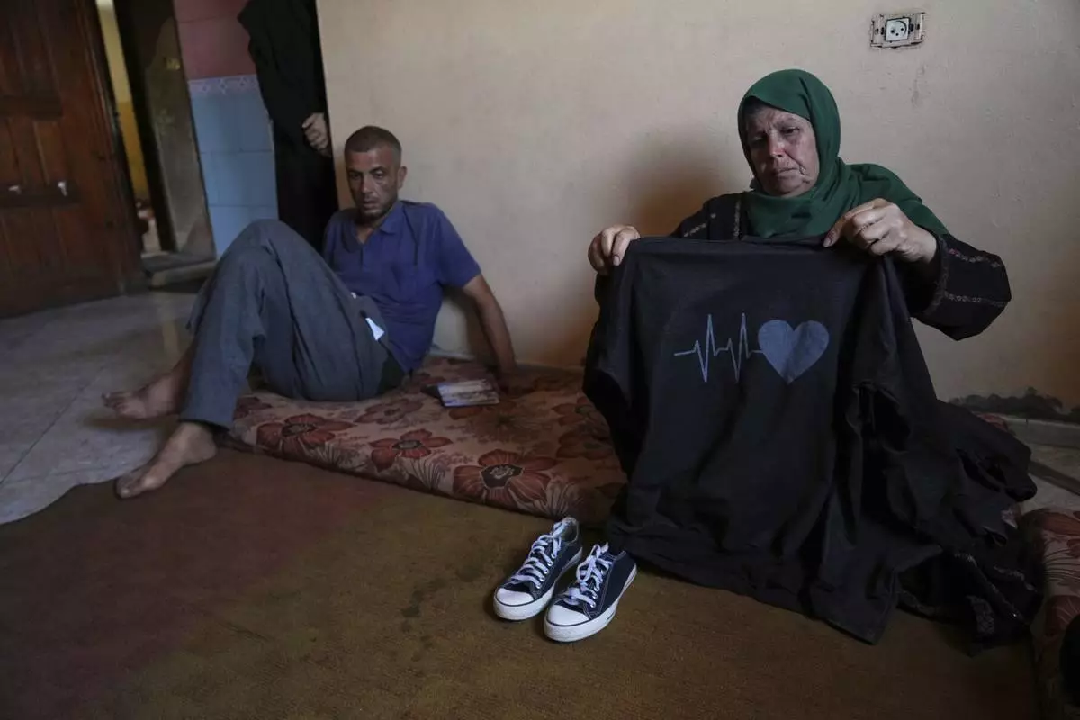Nahla Al-Nouri shows the clothes of 13-year-old Sama, one of her three grandchildren who were killed in an Israeli strike while waiting to receive nutritional supplements at a medical clinic, during an interview at the family home in Deir al-Balah, Gaza Strip, Friday, July 11, 2025. (AP Photo/Abdel Kareem Hana)