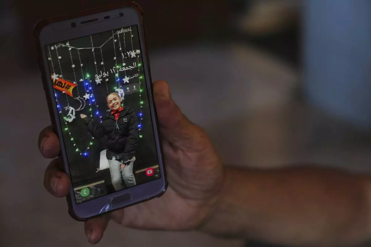 Nidal Al-Nouri shows a photo of his 13-year-old daughter Sama who was killed in an Israeli strike while waiting to receive nutritional supplements at a medical clinic, during an interview at his house in Deir al-Balah, Gaza Strip, Friday, July 11, 2025. (AP Photo/Abdel Kareem Hana)