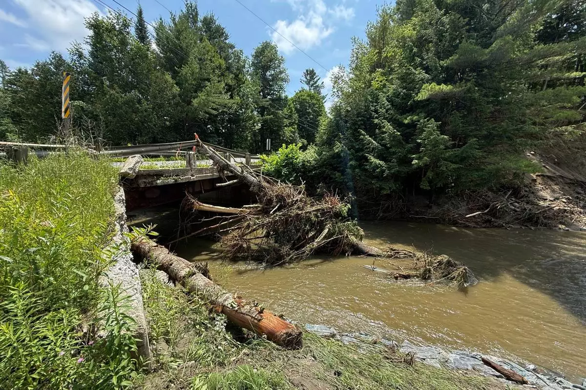 Damaged trees rest against a bridge after flash flooding in Sutton, Vt., Friday, July 11, 2025. (AP Photo/Amanda Swinhart)