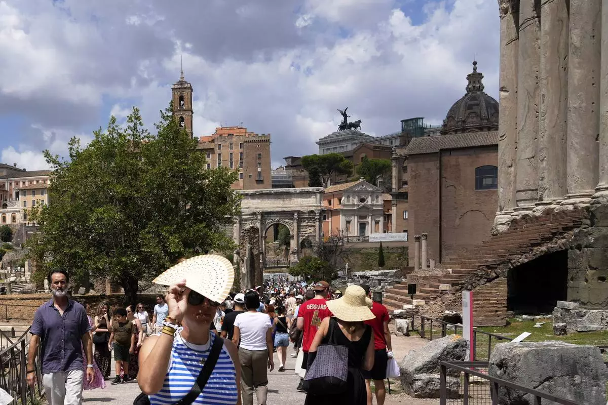 Tourists use use fans and sun hats as they visit the Forum in Rome on Tuesday, July 22, 2025. (AP Photo/Gregorio Borgia)