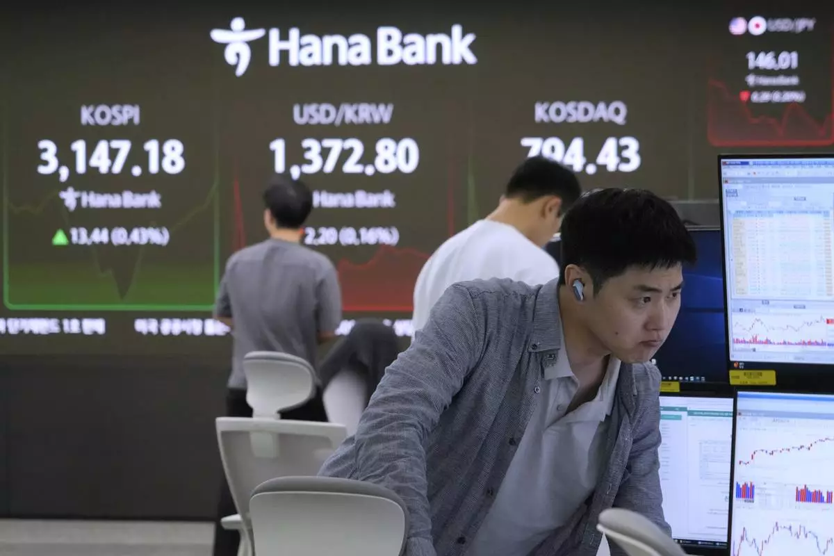 A currency trader watches monitors near a screen showing the Korea Composite Stock Price Index (KOSPI), top left, and the foreign exchange rate between U.S. dollar and South Korean won, top center, at the foreign exchange dealing room of the KEB Hana Bank headquarters in Seoul, South Korea, Thursday, July 10, 2025. (AP Photo/Ahn Young-joon)