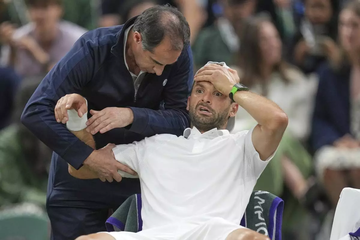 Bulgaria's Grigor Dimitrov gets treatment after he went down with an injury which forced him to retire injured from a fourth round men's singles match against Italy's Jannik Sinner at the Wimbledon Tennis Championships in London, Monday, July 7, 2025. (AP Photo/Kin Cheung)