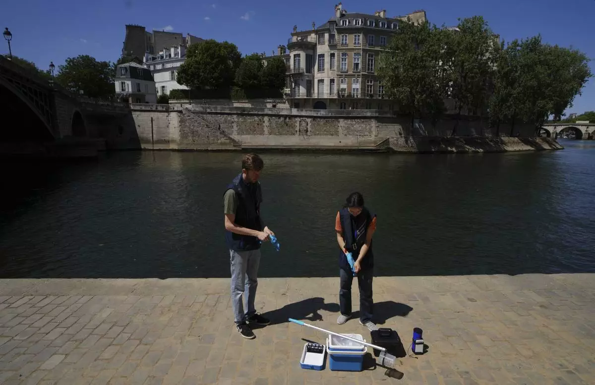 CORRECTS SURNAME TO HAGUET - Mathias Haguet, left, and Emilie Vilana of Fluidion test the Seine river water quality, Thursday, July 3, 2025 for the opening of the three Seine swimming pools during the 'Paris Plages' event from July 5 to Aug. 31 in Paris. (AP Photo/Aurelien Morissard)Sa
