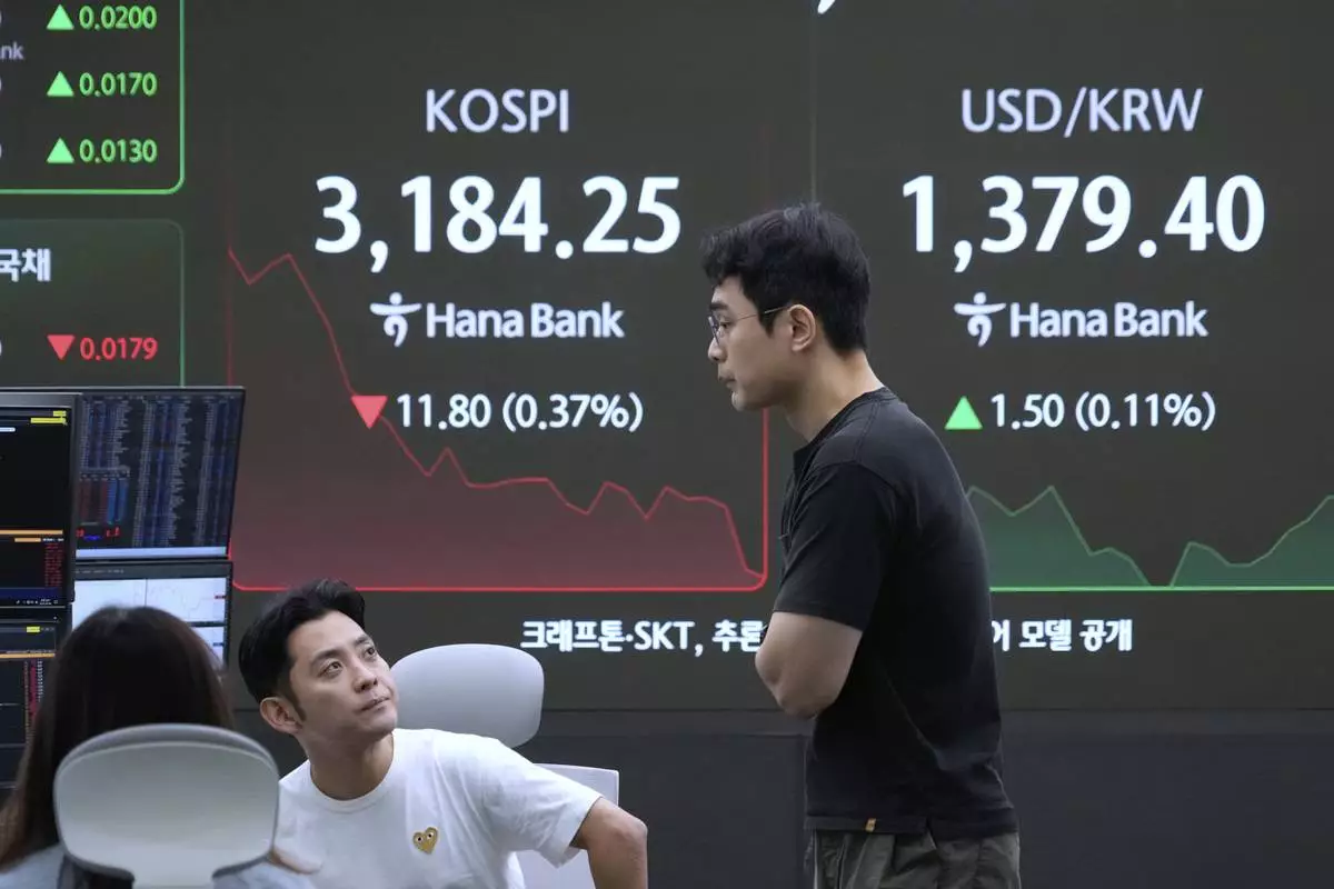 Currency traders work near a screen showing the Korea Composite Stock Price Index (KOSPI) and the foreign exchange rate between U.S. dollar and South Korean won, right, at the foreign exchange dealing room of the Hana Bank headquarters in Seoul, South Korea, Monday, July 28, 2025. (AP Photo/Ahn Young-joon)
