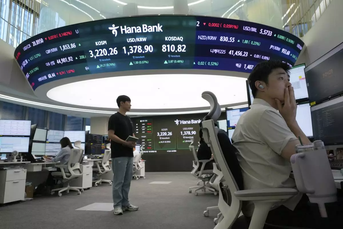 A currency trader watches monitors near a screen showing the Korea Composite Stock Price Index (KOSPI), top center left, and the foreign exchange rate between U.S. dollar and South Korean won, top center, at the foreign exchange dealing room of the Hana Bank headquarters in Seoul, South Korea, Monday, July 28, 2025. (AP Photo/Ahn Young-joon)