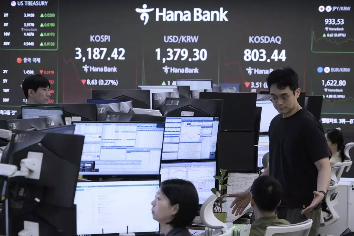 Currency traders work near a screen showing the Korea Composite Stock Price Index (KOSPI), top center left, and the foreign exchange rate between U.S. dollar and South Korean won, top center, at the foreign exchange dealing room of the Hana Bank headquarters in Seoul, South Korea, Monday, July 28, 2025. (AP Photo/Ahn Young-joon)