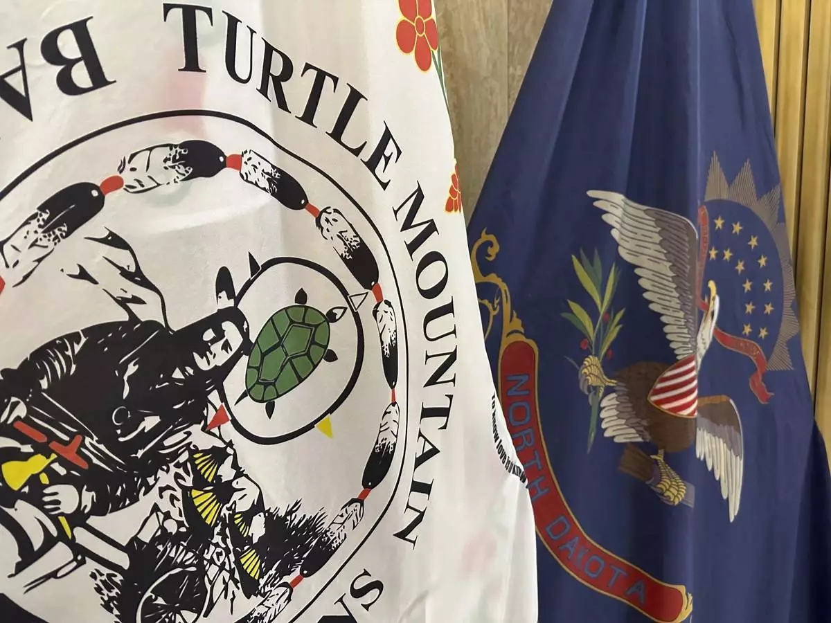 FILE - Flags for the Turtle Mountain Band of Chippewa Indians and the state of North Dakota stand in Memorial Hall of the state Capitol in Bismarck, N.D., on Dec. 15, 2023. (AP Photo/Jack Dura, File)