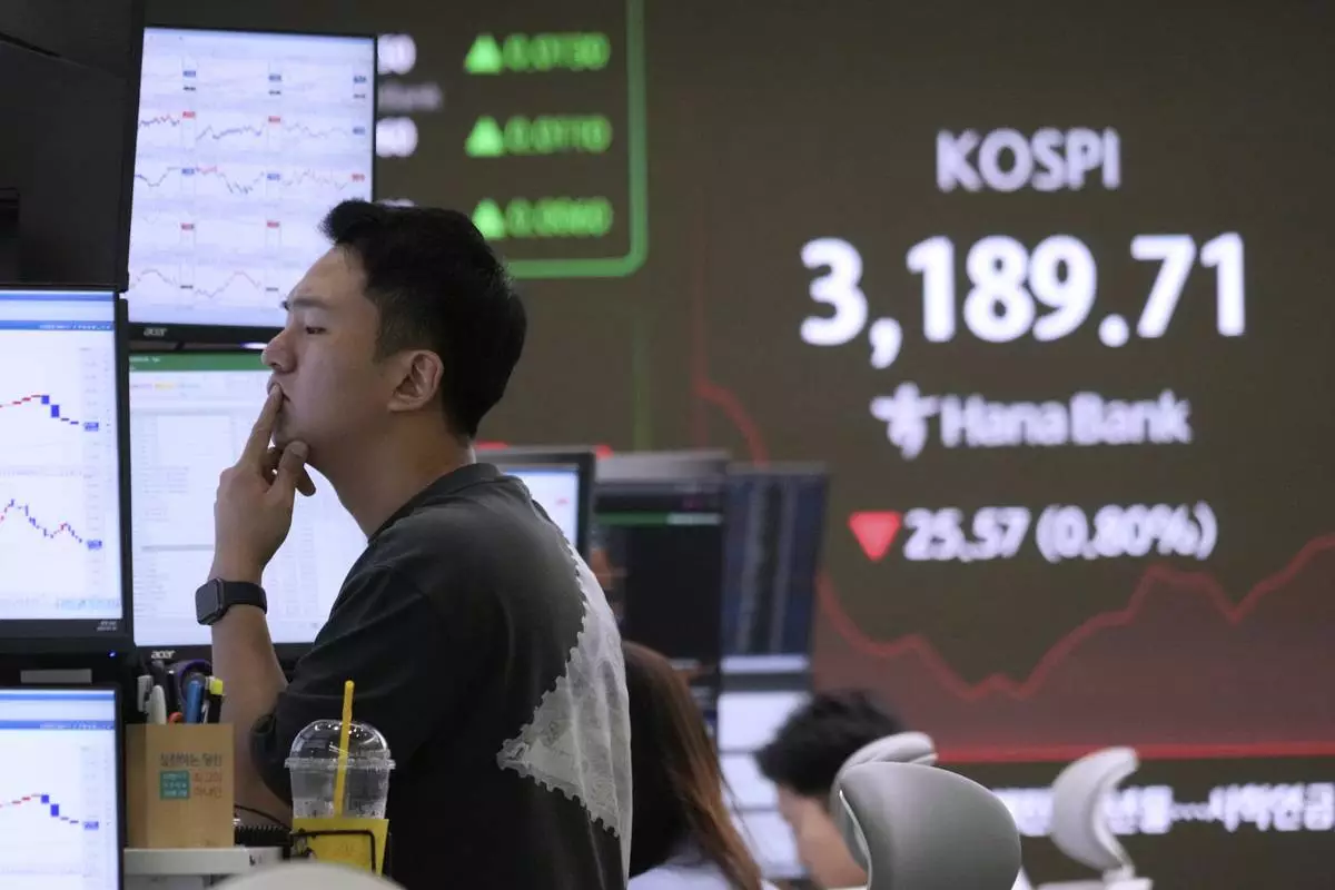 A currency trader watches monitors near a screen showing the Korea Composite Stock Price Index (KOSPI) at the foreign exchange dealing room of the Hana Bank headquarters in Seoul, South Korea, Wednesday, July 16, 2025. (AP Photo/Ahn Young-joon)