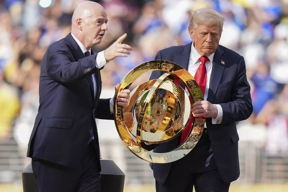 FIFA President Gianni Infantino, left, and President Donald Trump carry the championship trophy after the Club World Cup final soccer match between Paris Saint-Germain and Chelsea in East Rutherford, N.J., Sunday, July 13, 2025. (AP Photo/Frank Franklin II)