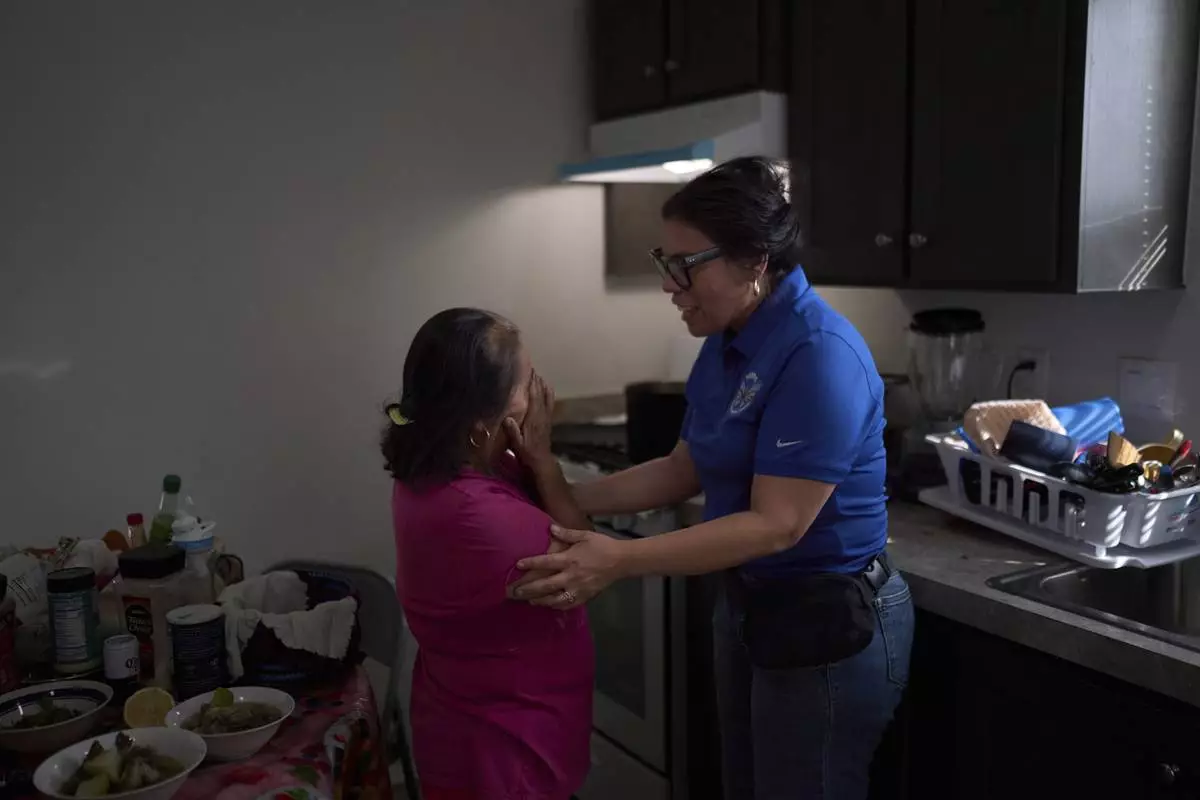 Martha, a mobile home resident, breaks down while speaking with Luz Gallegos, executive director of the immigrant and farmworker justice group TODEC, in Oasis, Calif., Monday, April 14, 2025, after picking up cases of bottled water provided by the organization. (AP Photo/Jae C. Hong)