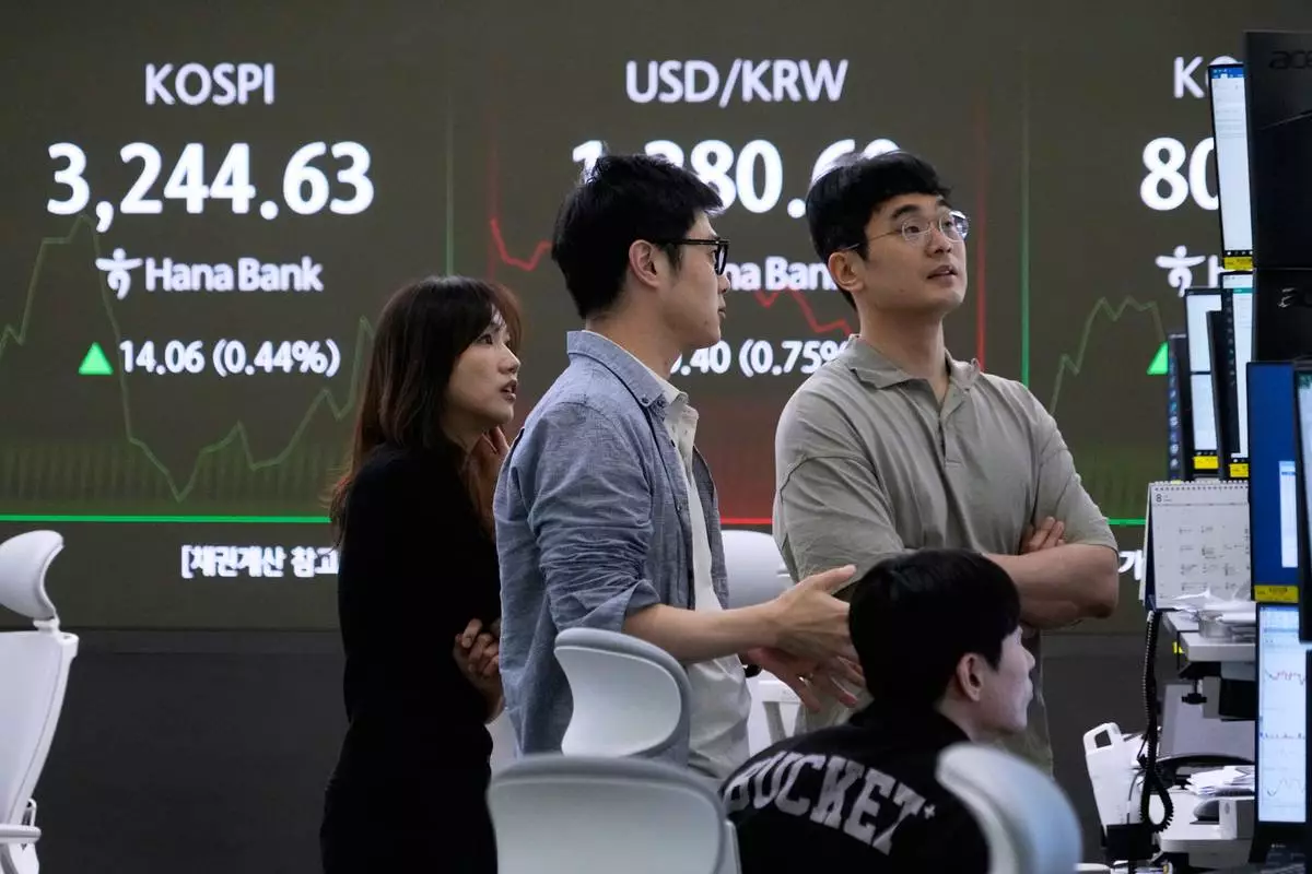 Currency traders watch monitors near a screen showing the Korea Composite Stock Price Index (KOSPI), left, and the foreign exchange rate between U.S. dollar and South Korean won at the foreign exchange dealing room of the Hana Bank headquarters in Seoul, South Korea, Wednesday, July 30, 2025. (AP Photo/Ahn Young-joon)