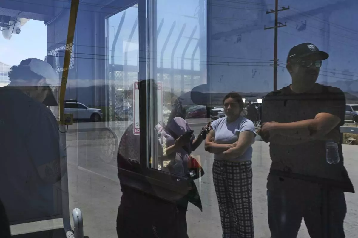 People wait outside of Glass House Farms, a day after an immigration raid on the facility, Friday, July 11, 2025, in Camarillo, Calif. (AP Photo/Jae C. Hong)