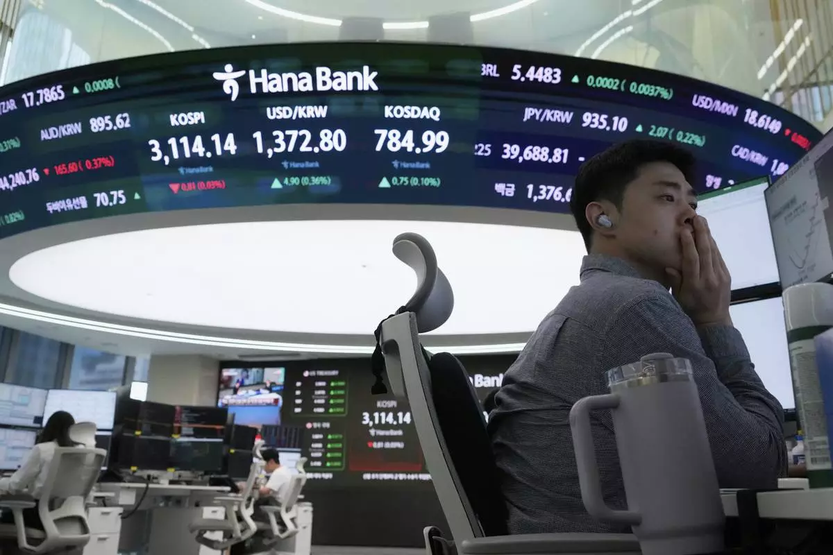 A currency trader watches monitors near a screen showing the Korea Composite Stock Price Index (KOSPI), top center left, and the foreign exchange rate between U.S. dollar and South Korean won, top center, at the foreign exchange dealing room of the Hana Bank headquarters in Seoul, South Korea, Wednesday, July 9, 2025. (AP Photo/Ahn Young-joon)