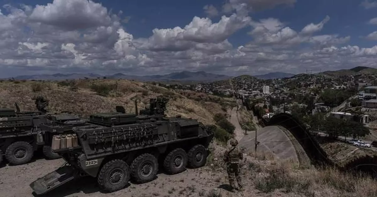 A man is halted climbing the US-Mexico border wall. Under new Trump rules, US troops sound the alarm