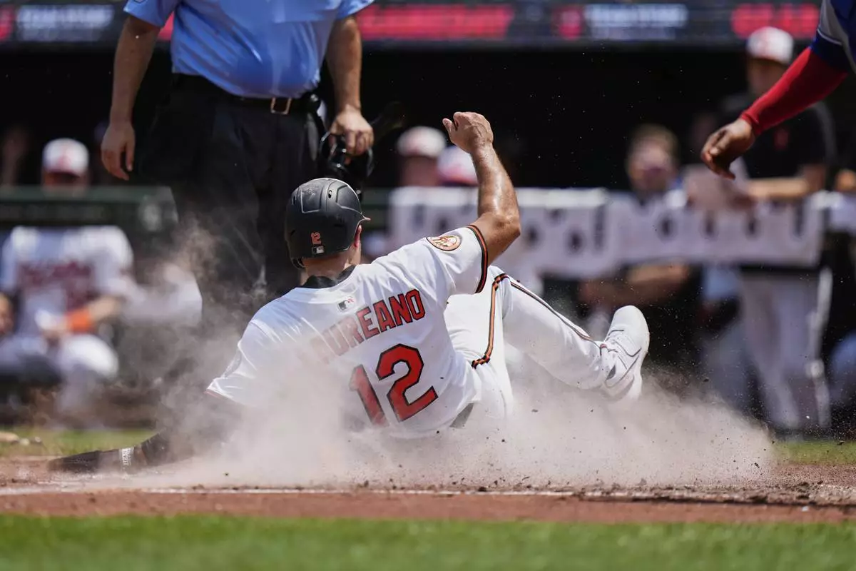 CORRECTS INNING TO THIRD, NOT FIRST - Baltimore Orioles' Ramon Laureano (12) slides into home plate to score on a sacrifice fly hit by Ramon Urias during the third inning in the first baseball game of a doubleheader against the Toronto Blue Jays, Tuesday, July 29, 2025, in Baltimore. (AP Photo/Stephanie Scarbrough)
