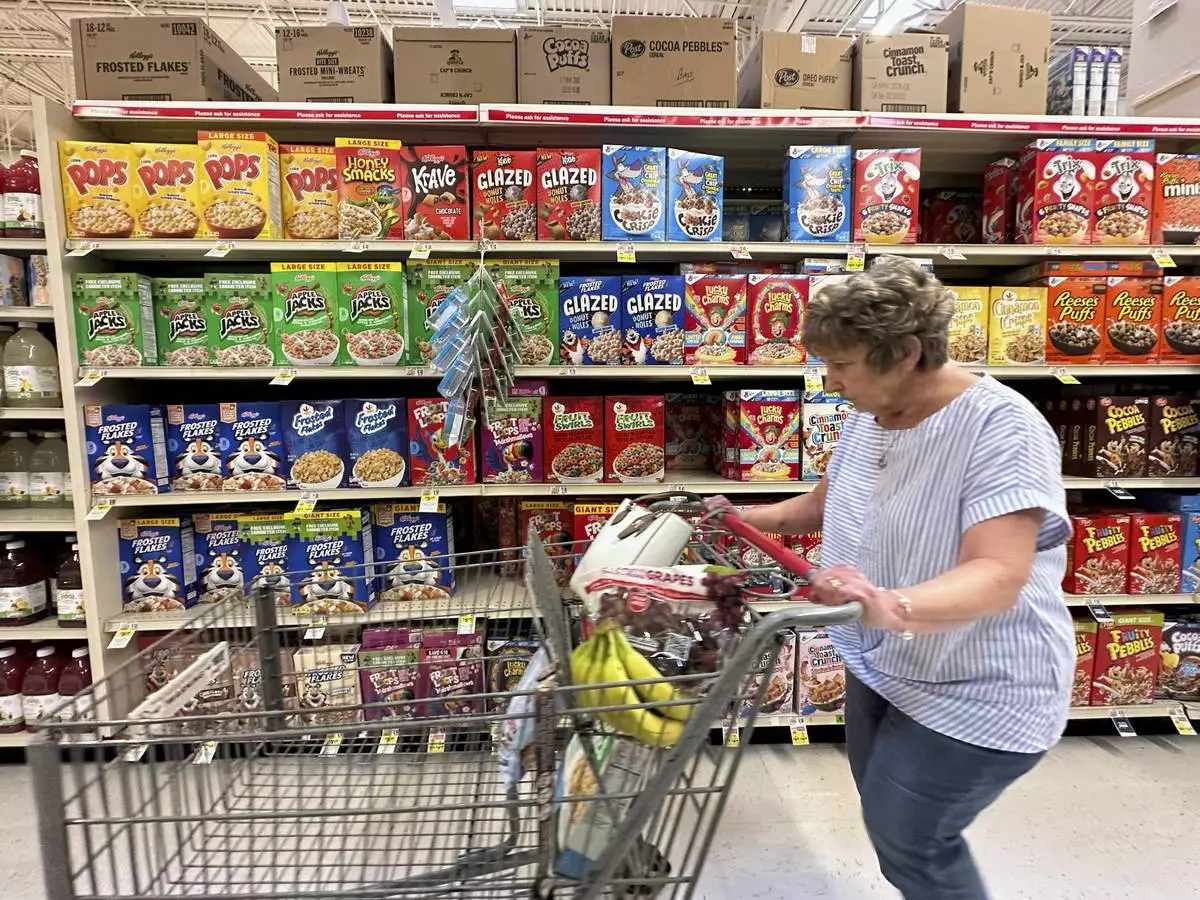 A woman pushes a shopping cart past boxes of Kellogg's breakfast cereal at a supermarket, Friday, July 11, 2025, in Springfield, Pa. (AP Photo/Matt Slocum)