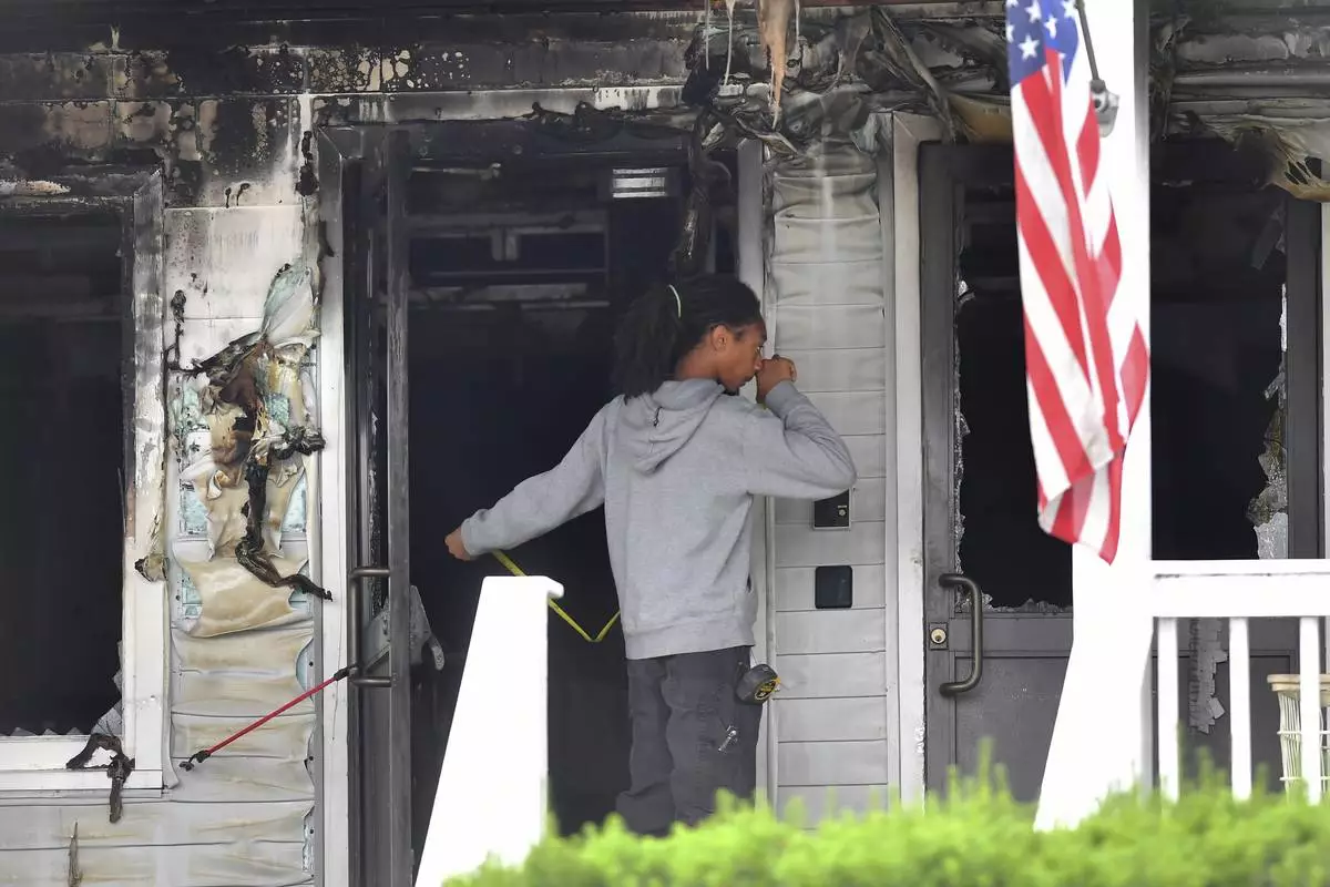 An investigator takes measurements Monday, July 14, 2025, near an entrance to the Gabriel House assisted living facility following a fire that started late Sunday, in Fall River, Mass. (AP Photo/Steven Senne)