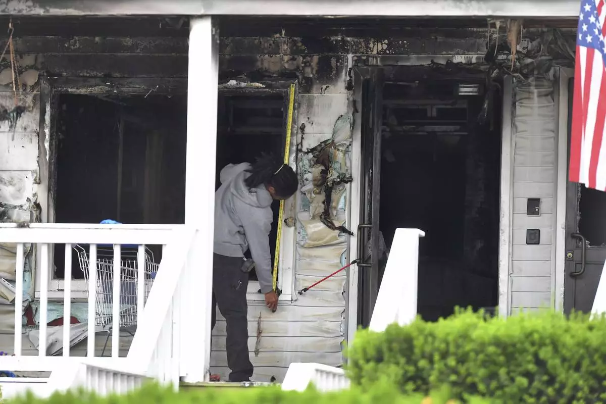 An investigator takes measurements Monday, July 14, 2025, near an entrance to the Gabriel House assisted living facility following a fire that started late Sunday in Fall River, Mass. (AP Photo/Steven Senne)