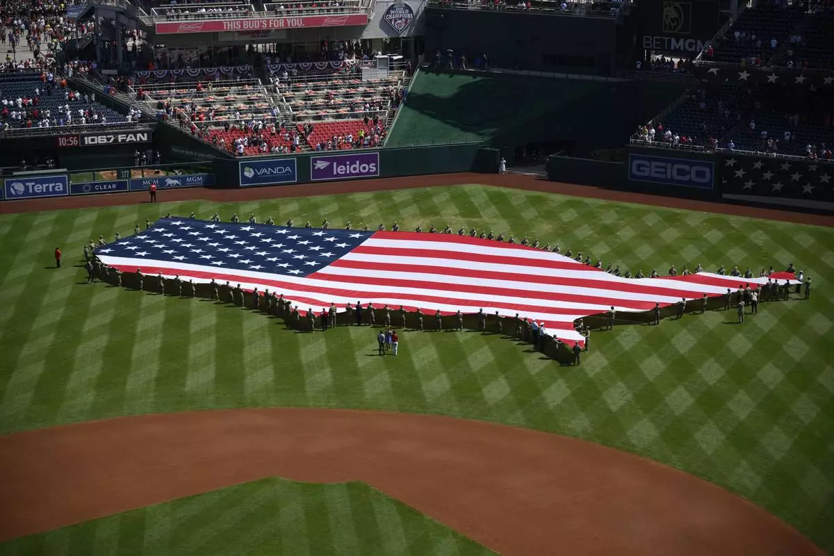 An American flag in the shape of the continental United States is displayed on the field before a baseball game between the Washington Nationals and the Boston Red Sox, Friday, July 4, 2025, in Washington. (AP Photo/Nick Wass)