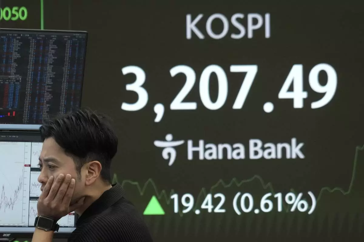 A currency trader watches monitors near a screen showing the Korea Composite Stock Price Index (KOSPI) at the foreign exchange dealing room of the Hana Bank headquarters in Seoul, South Korea, Monday, July 21, 2025. (AP Photo/Ahn Young-joon)