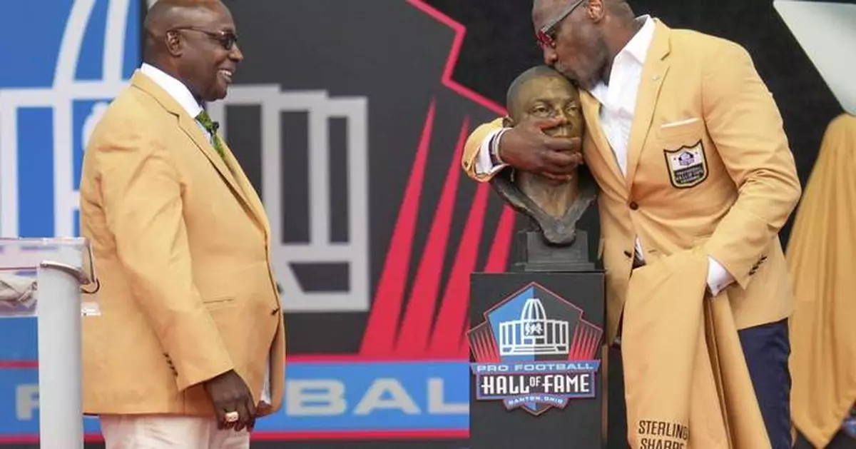 Sterling Sharpe gives fellow Pro Football Hall of Fame brother Shannon his gold jacket