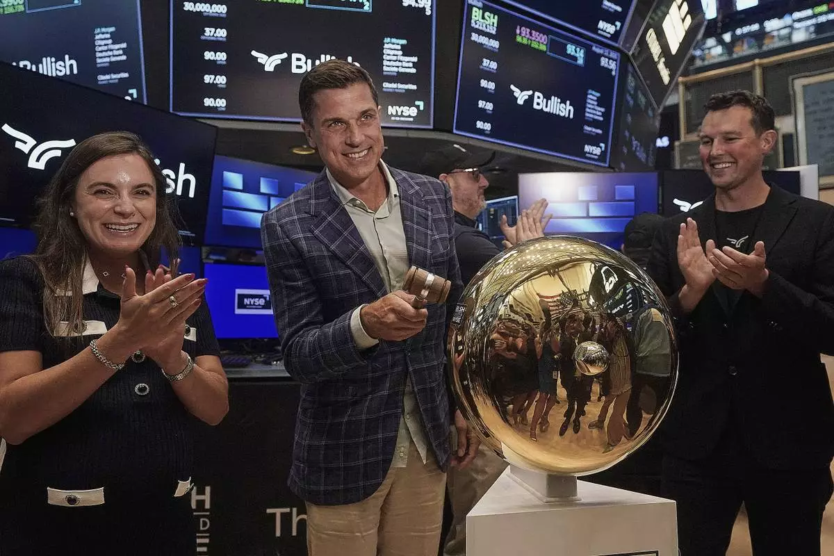 Bullish CEO Tom Farley, center, is flanked by Coin Desk CEO Sara Stratiberdha, and Bullish Chairman Brendan Blumer, as he rings the ceremonial bell when the company's IPO begins trading on the floor of the New York Stock Exchange, Wednesday, Aug. 13, 2025. (AP Photo/Richard Drew)