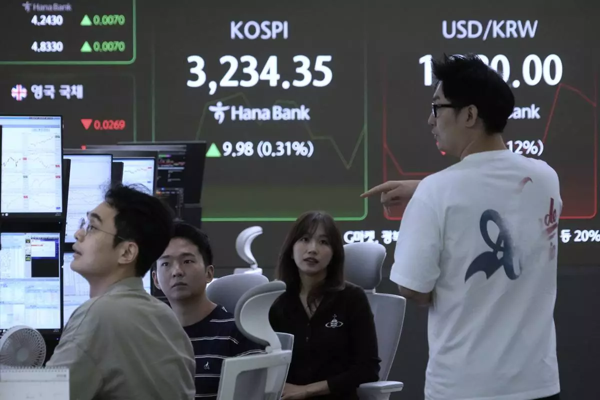 Currency traders work near a screen showing the Korea Composite Stock Price Index (KOSPI) and the foreign exchange rate between U.S. dollar and South Korean won, right, at the foreign exchange dealing room of the Hana Bank headquarters in Seoul, South Korea, Thursday, Aug. 14, 2025. (AP Photo/Ahn Young-joon)