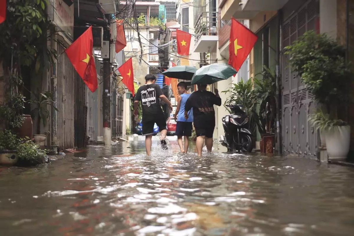 People wade through a flooded alley caused by Typhoon Kajiki in Hanoi, Vietnam, Tuesday, Aug. 26, 2025. (AP Photo/Huy Han)