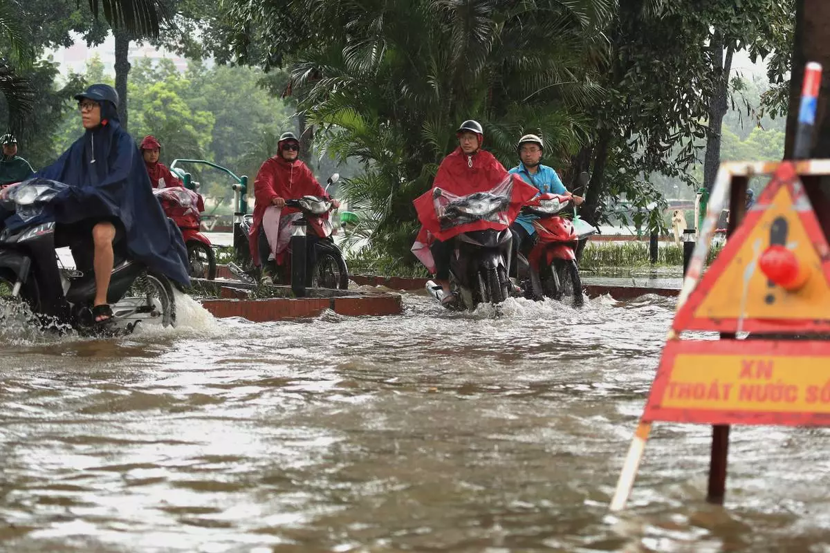People drive motorcycles on a flooded street caused by Typhoon Kajiki in Hanoi, Vietnam, Tuesday, Aug. 26, 2025. (AP Photo/Huy Han)