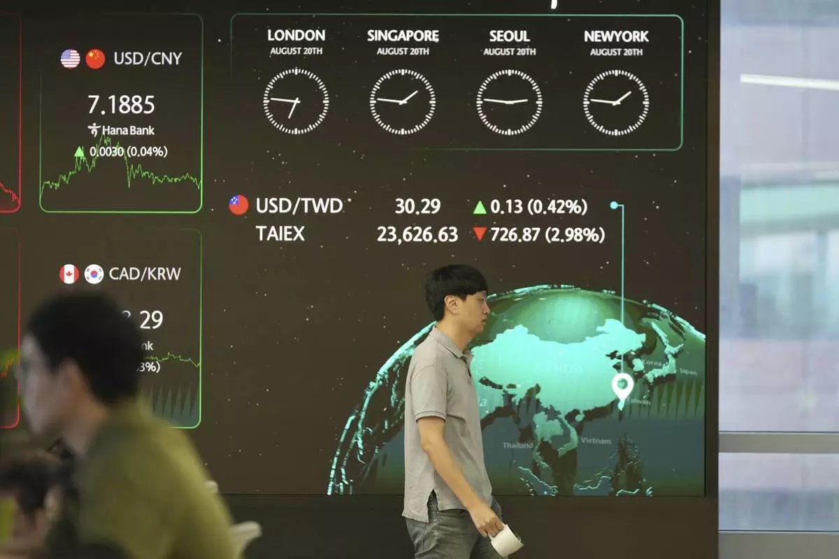 A dealer walks near screens showing the foreign exchange rates at a dealing room of Hana Bank in Seoul, South Korea, Wednesday, Aug. 20, 2025. (AP Photo/Lee Jin-man)