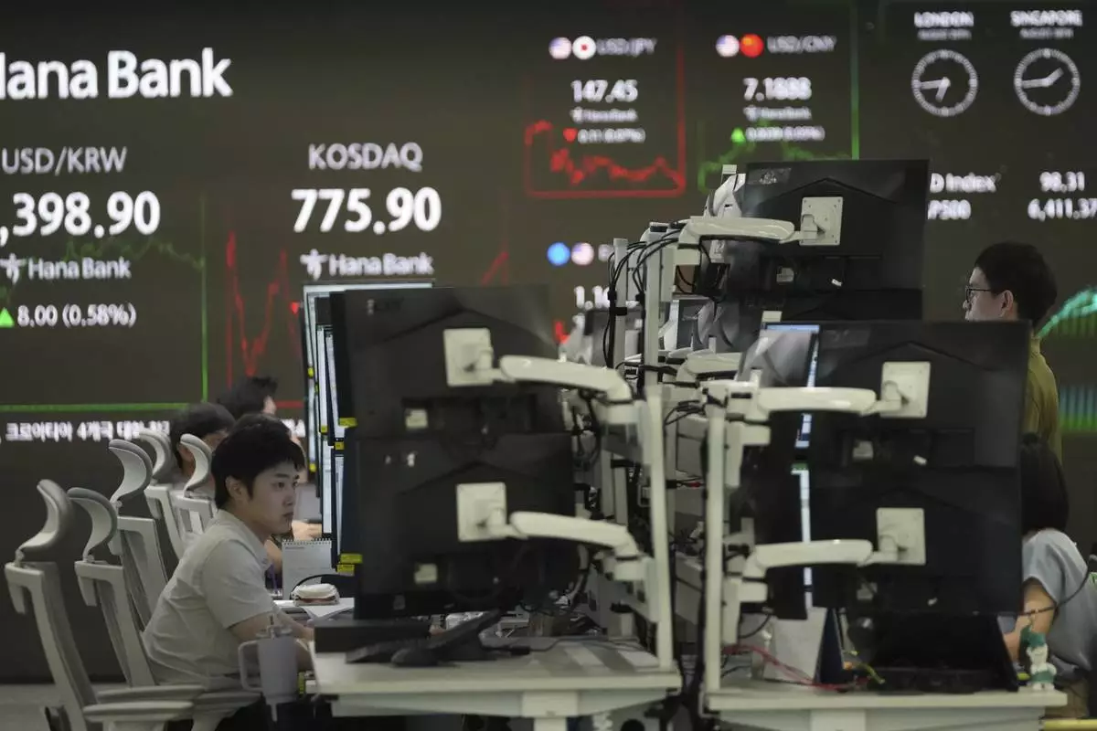 Dealers watch computer monitors near screens showing the foreign exchange rate between U.S. dollar and South Korean won and the Korean Securities Dealers Automated Quotations (KOSDAQ) at a dealing room of Hana Bank in Seoul, South Korea, Wednesday, Aug. 20, 2025. (AP Photo/Lee Jin-man)