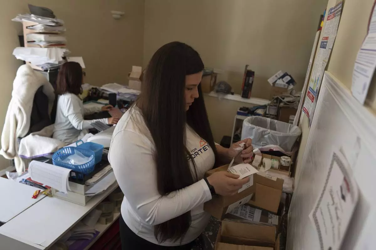 CORRECTS COMPANY NAME: Amanda Follett works on packages at A Sight For Sport Eyes, a brick-and-mortar and e-commerce store for sport goggles, Aug. 20, 2025, in West Linn, Ore. (AP Photo/Jenny Kane)