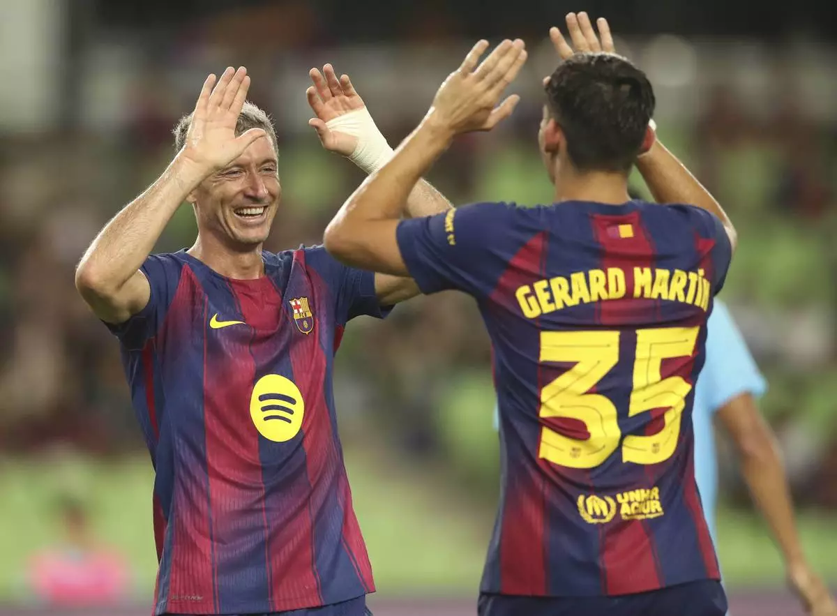 FC Barcelona's Robert Lewandowski, left, celebrates with his teammate Gerard Martin after scoring a goal during a friendly soccer match between FC Barcelona and Daegu FC at the Daegu Stadium in Daegu, South Korea, Monday, Aug. 4, 2025. (Kim Hyun-tea/Yonhap via AP)