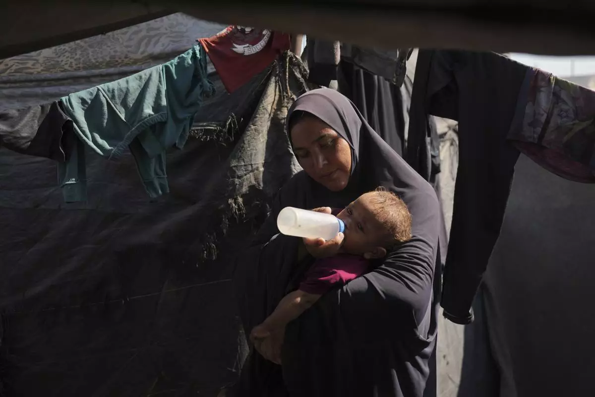Abeer Sobh uses a feeding bottle to give water to her baby inside their tent at a camp for displaced Palestinians, where she and her family are sheltering in Gaza City, Thursday, July 24, 2025. (AP Photo/Jehad Alshrafi)