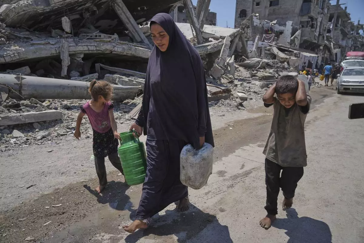 Abeer Sobh and her children carry water in plastic jerrycans after collecting it from a water truck in Gaza City, Thursday, July 24, 2025. (AP Photo/Jehad Alshrafi)