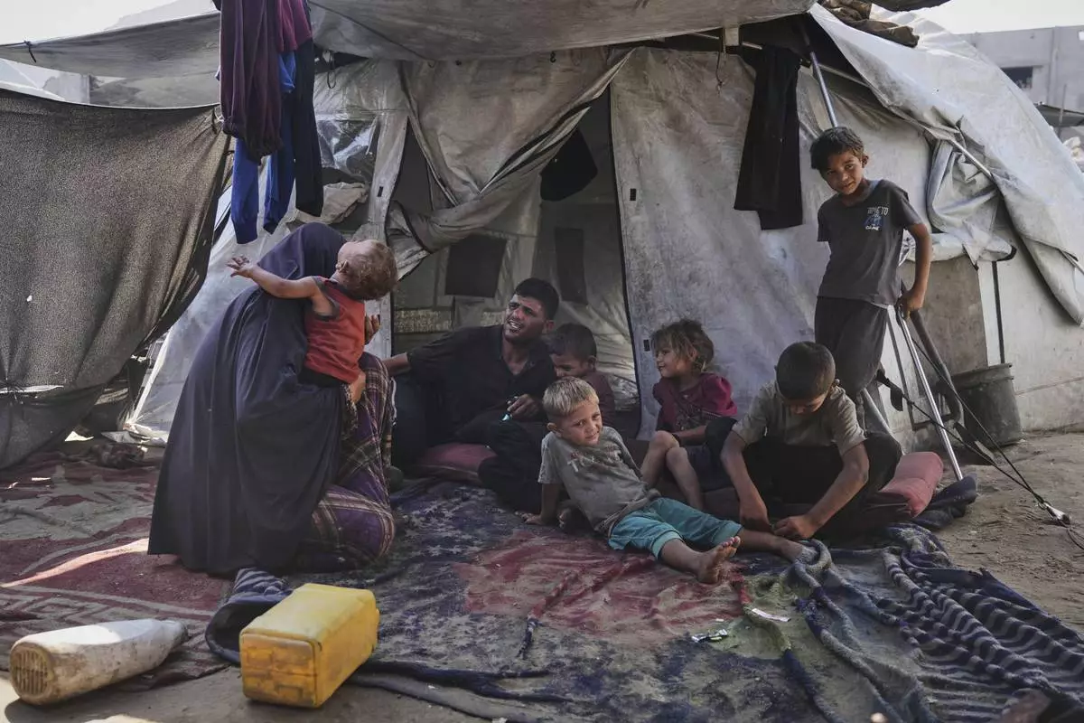 Abeer and Fadi Sobh gather in their tent with their children at a camp for displaced Palestinians in Gaza City, Thursday, July 24, 2025. (AP Photo/Jehad Alshrafi)