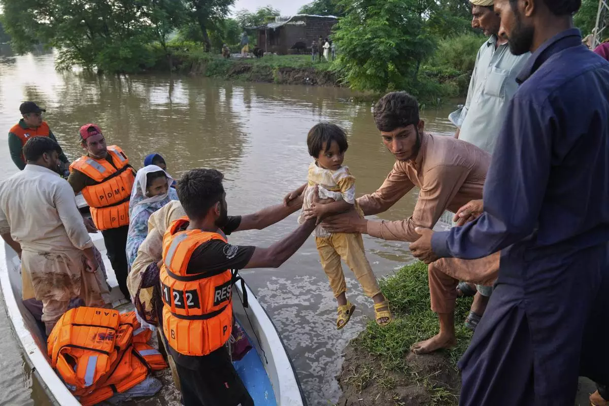 A rescue worker helps villagers evacuated from a flooded area of Chango Walia village, in Narowal district, Pakistan, Wednesday, Aug. 27, 2025. (AP Photo/K.M. Chaudary)