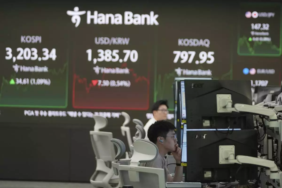 A dealer watches computer monitors near the screens showing the Korea Composite Stock Price Index (KOSPI), left, the foreign exchange rate between U.S. dollar and South Korean won and the Korean Securities Dealers Automated Quotations (KOSDAQ) at a dealing room of Hana Bank in Seoul, South Korea, Monday, Aug. 25, 2025. (AP Photo/Lee Jin-man)