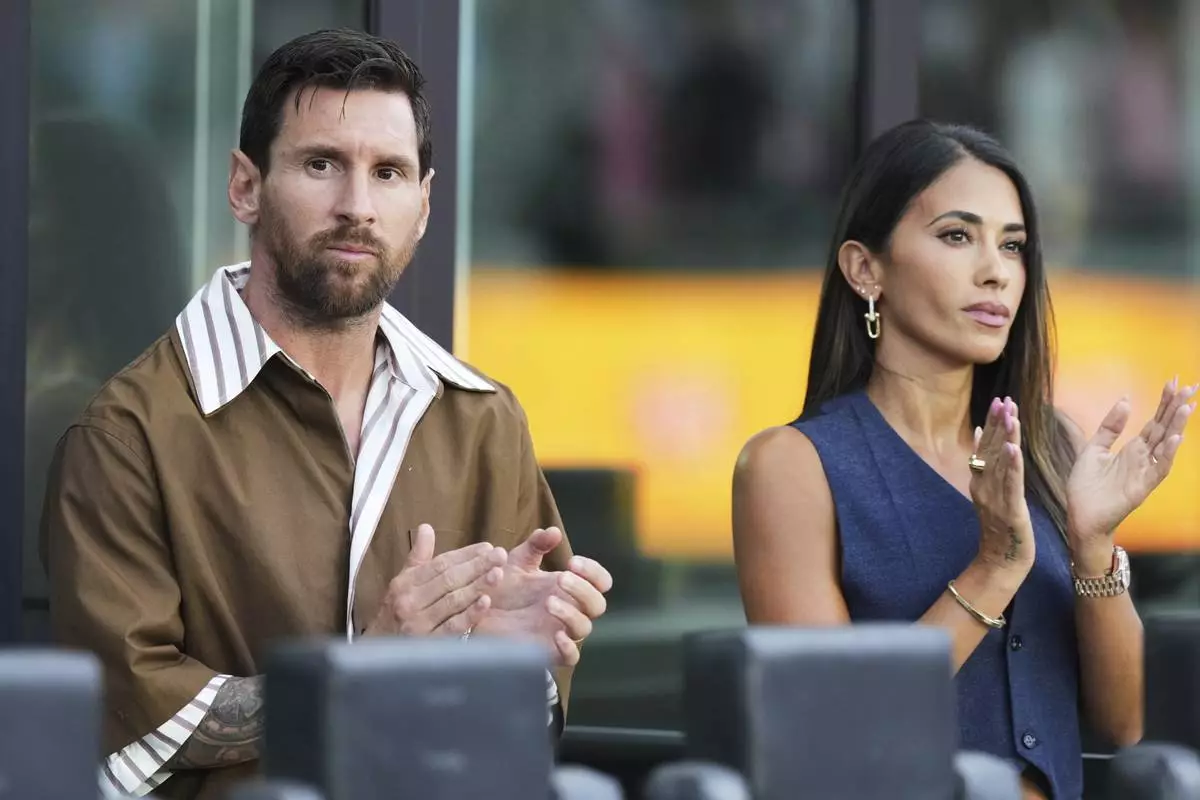 Inter Miami forward Lionel Messi, left, sits with his wife Antonela Roccuzzo, right, before a Leagues Cup soccer match against Pumas UNAM, Wednesday, Aug. 6, 2025, in Fort Lauderdale, Fla. (AP Photo/Lynne Sladky)
