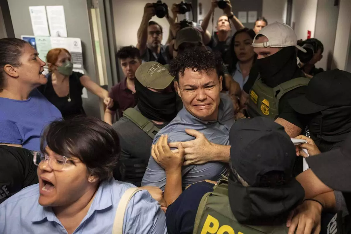 Federal agents detain Carlos Javier Lopez Benitez, center, of Paraguay, as they pull away his sister, Porfiria Lopez, a U.S. citizen, front left, outside an immigration court at the Jacob K. Javits federal building in New York, July 16, 2025. (AP Photo/Yuki Iwamura)