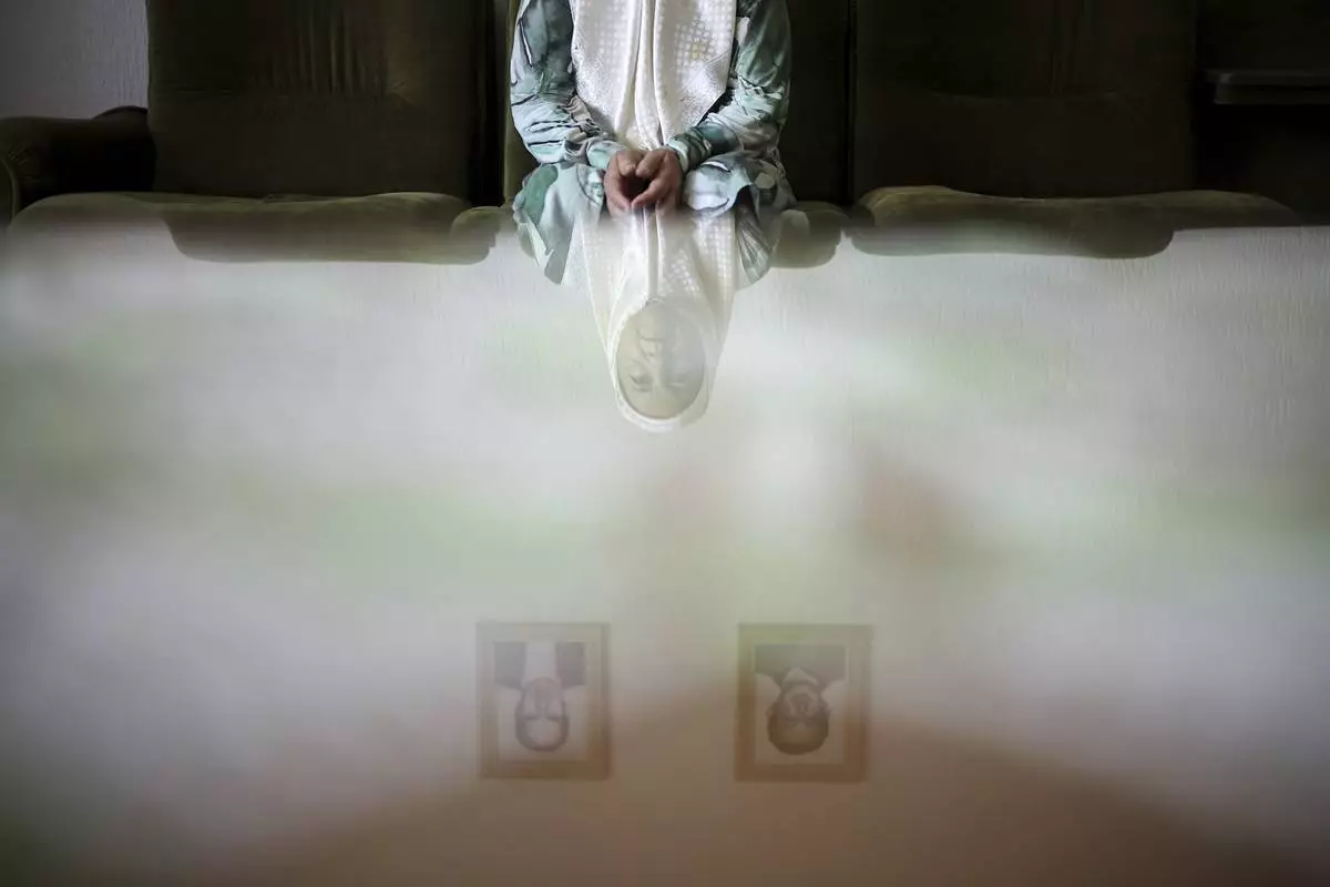 Fadila Efendic, 74, reflected on a table, sits in her living room under pictures of her son and husband, victims of the Srebrenica genocide, in the village of Potocari near Srebrenica, Bosnia, June 28, 2025. Efendic lost a total of 22 members of her family to the genocide. (AP Photo/Armin Durgut)