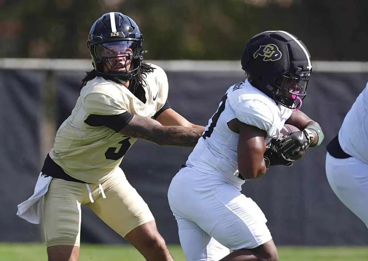 Colorado quarterback Kaidon Salter, left, hands off the ball to running back Micah Welch during NCAA college football practice, Thursday, Aug. 14, 2025, in Boulder, Colo.(AP Photo/David Zalubowski)