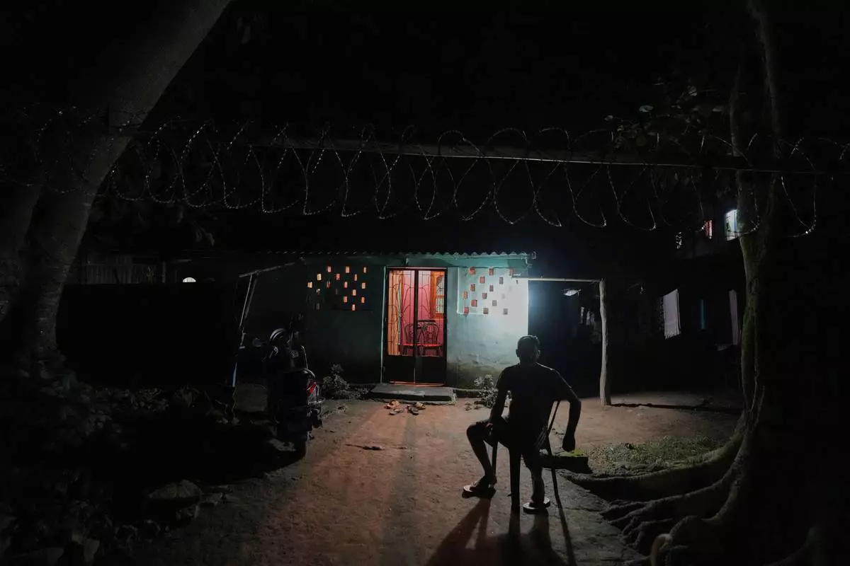 A resident keeps guard, watching for wild elephants, outside his home near Amchang wildlife sanctuary on the outskirts of Guwahati, Saturday, Aug. 9, 2025. (AP Photo/Anupam Nath)