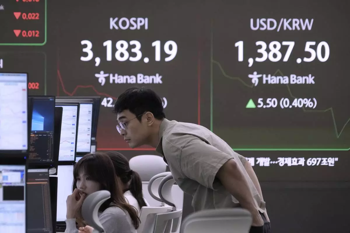Currency traders watch monitors near a screen showing the Korea Composite Stock Price Index (KOSPI), left, and the foreign exchange rate between U.S. dollar and South Korean won at the foreign exchange dealing room of the Hana Bank headquarters in Seoul, South Korea, Monday, Aug. 18, 2025. (AP Photo/Ahn Young-joon)