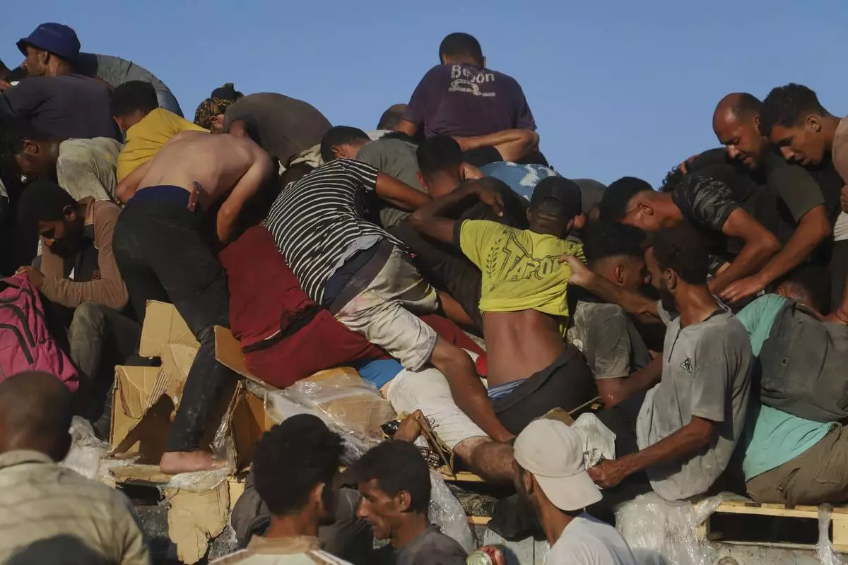 Palestinians ride on a truck loaded with food and humanitarian aid as it moves along the Morag corridor near Rafah, in the southern Gaza Strip, Aug. 4, 2025. (AP Photo/Mariam Dagga)