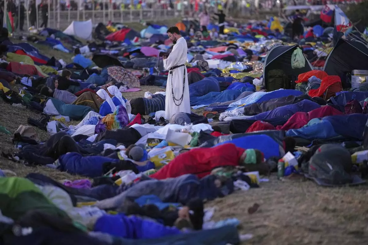 A priest stands amid young people camping out on the Tor Vergata field, before the start of a Mass led by Pope Francis celebrating the Jubilee of the Catholic Church, in Rome, Aug. 3, 2025. (AP Photo/Andrew Medichini)