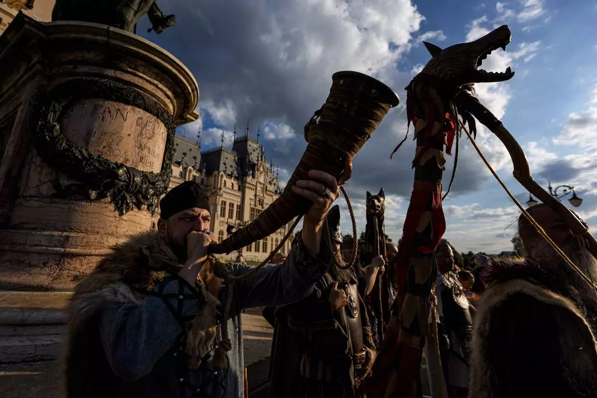 A man blows a horn as history buffs wearing Dacian warrior and Roman soldiers outfits march in Iasi, Romania, Friday, July 11, 2025 ahead of the Getodava historical reenactment festival. (AP Photo/Andreea Alexandru)